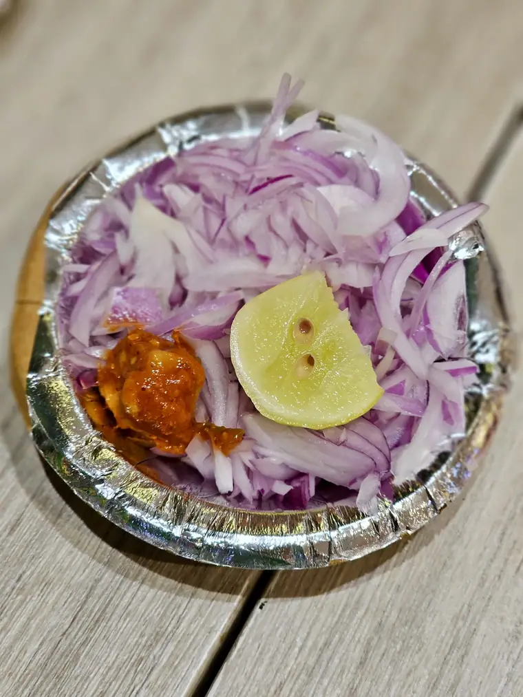 Sliced red onion with lime and pickle on a small plate