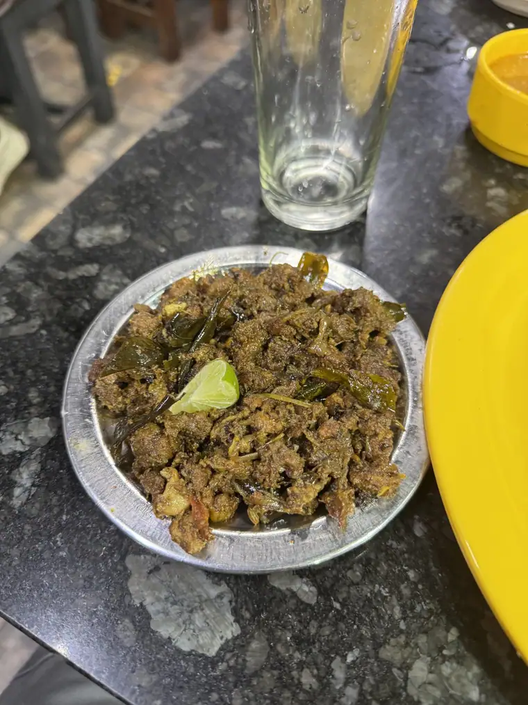 A steel plate of dark beef fry with a wedge of lime