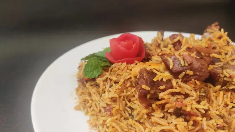 Tamil Nadu style biryani with chunks of meat on a white plate